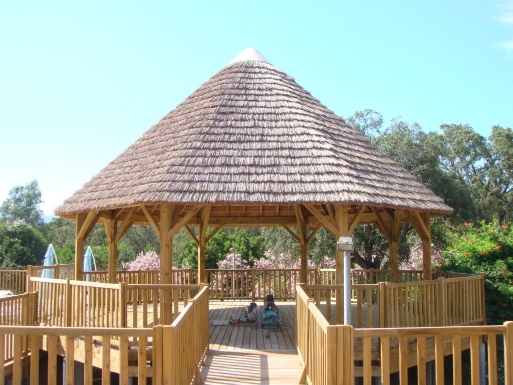 Grande paillote ronde au milieu d’une piscine zoom sur une paillote Ekolinea avec une couverture en roseau et charpente en bois. Ekolinea est spécialiste des Parasols exotiques et paillotes