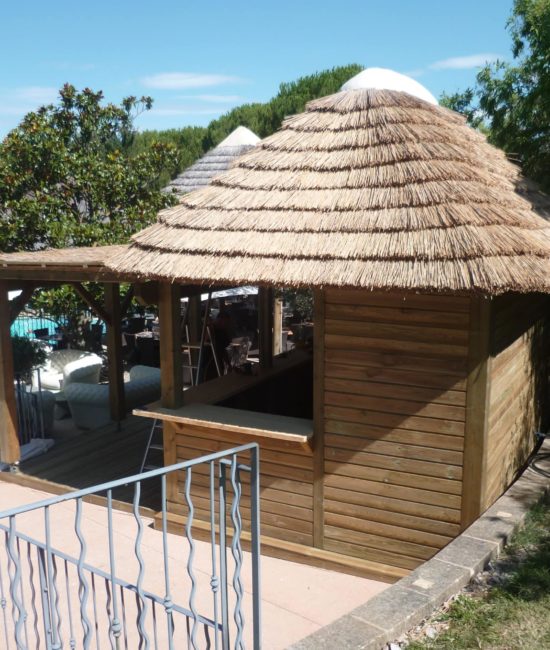 Vue sur une paillote avec un toit traditionnel en roseau de camargue et une pergola. Ekolinea est spécialiste des Parasols exotiques et paillotes