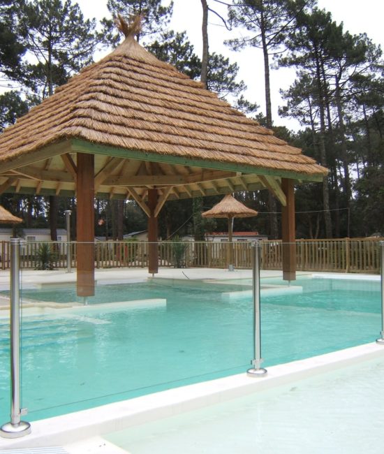 vue sur une paillote recouvrant une partie de la piscine pour créer de l'ombre. La couverture du toit est en roseau de camargue. Ekolinea est spécialiste des Parasols exotiques et paillotes