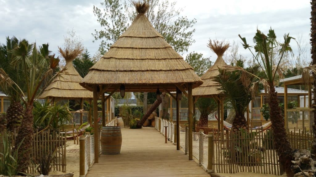 Parasol paillote en roseau d’une allée de camping zoom sur la paillote Fiesta de Ekolinea avec sa couverture de toit en roseau de camargue. Ekolinea est spécialiste des Parasols exotiques et paillotes