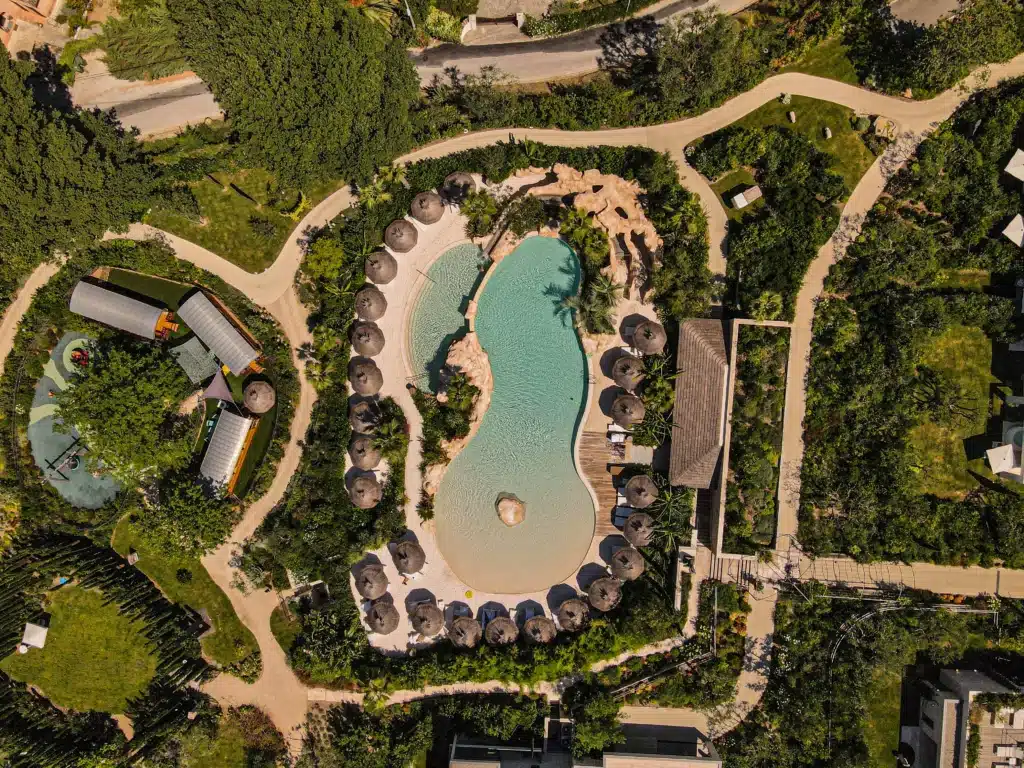 Domaine du Mas de Pierre Lagon Parasol Vue aérienne du Domaine du Mas de Pierre et de son Lagon. Installation de parasols tropicaux sur la plage de la piscine