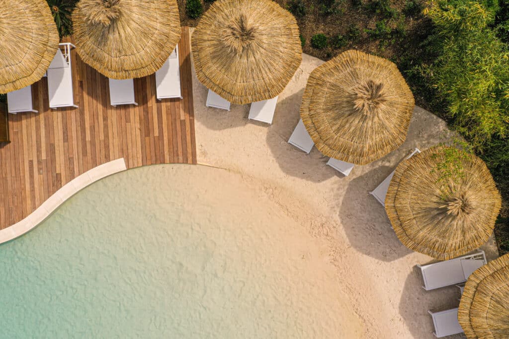 Vue aerienne du Domaine du Mas de PIerre Terrasse et parasols du Lagon de l'hôtel 5 étoiles : le Domaine du Mas de Pierre