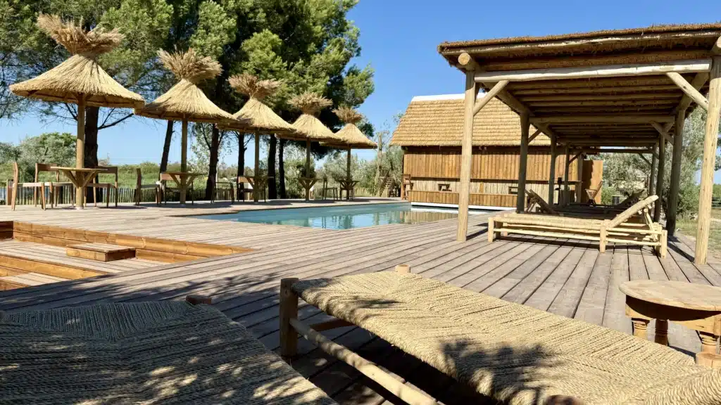 Espace piscine Mas de Dard Aménagements de l'espace piscine du Mas de Dard : terrasses en bois, pergolas en bois, parasols en roseau, paillote bar avec couverture de toit en roseau