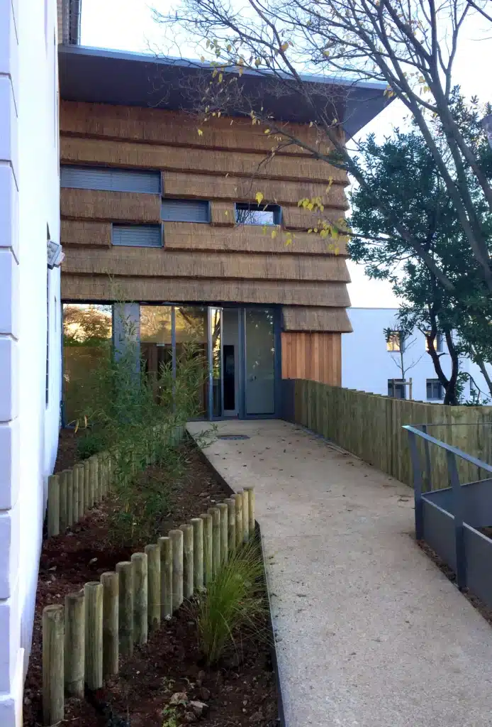 Bardage roseau d'un bâtiment Bardage en roseau et en bois d'un bâtiment d'une collectivité locale. Structure bois et pose du roseau.