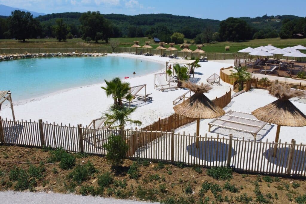Domaine de la Besse et Ekolinea Installation de mobilier (chilienne en bois) et de parasols camarguais autour de la piscine lagon du Domaine de la Besse en Ariège